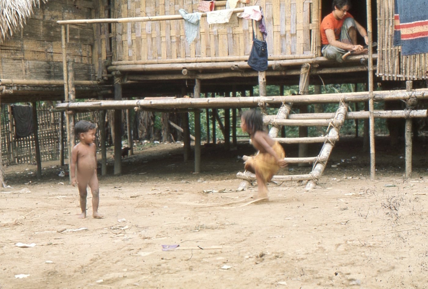 Temiar village in the 1970s, with Andy Hickson sitting in a doorway.