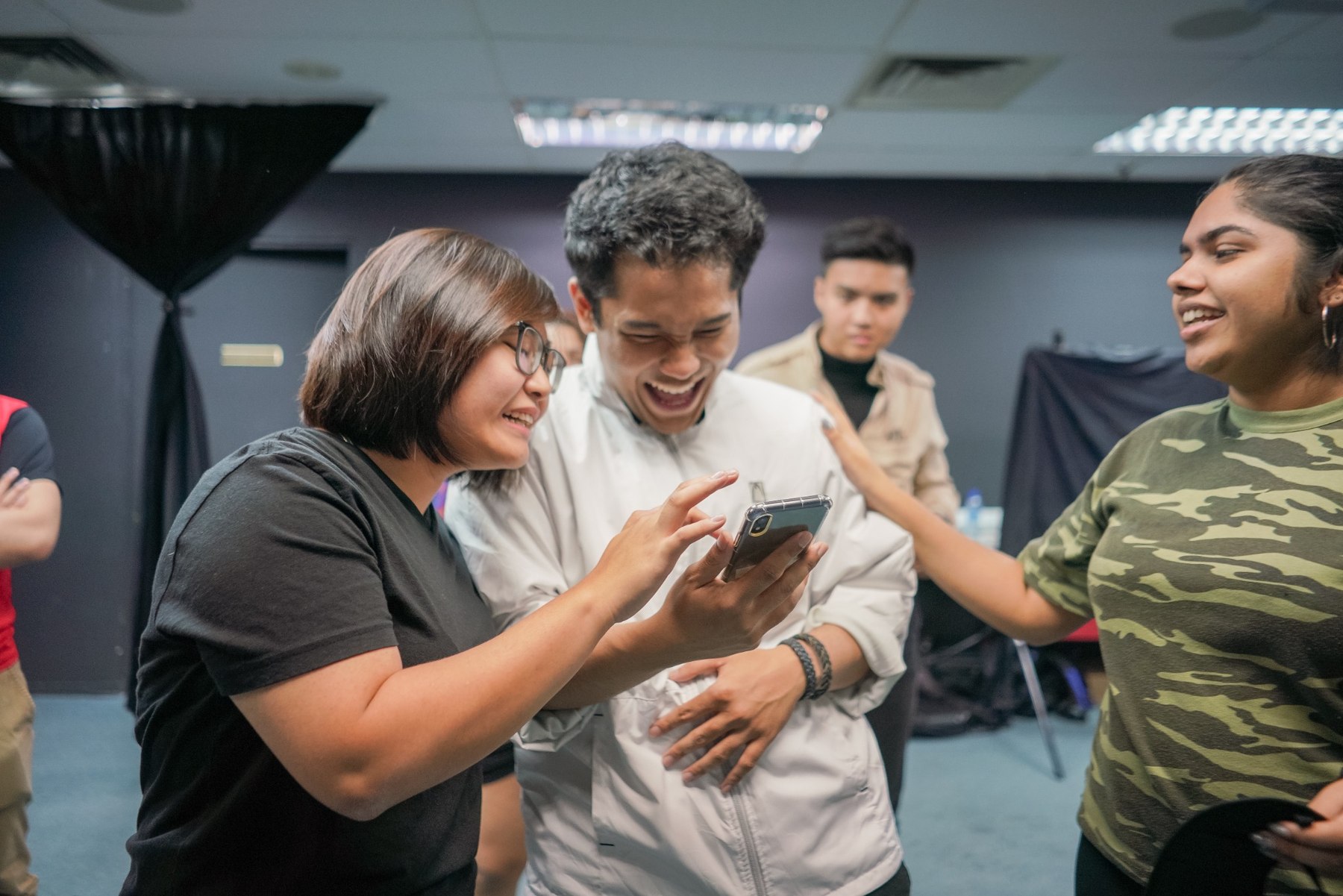 Young people gathered around a mobile phone during a workshop